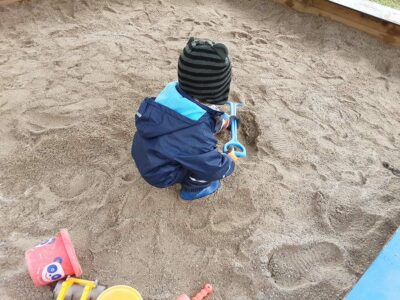 Krippenkind spielt im Sand